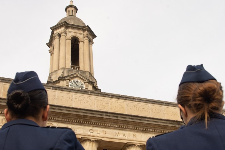 Two Air Force females in uniform looking up a Old Main. 